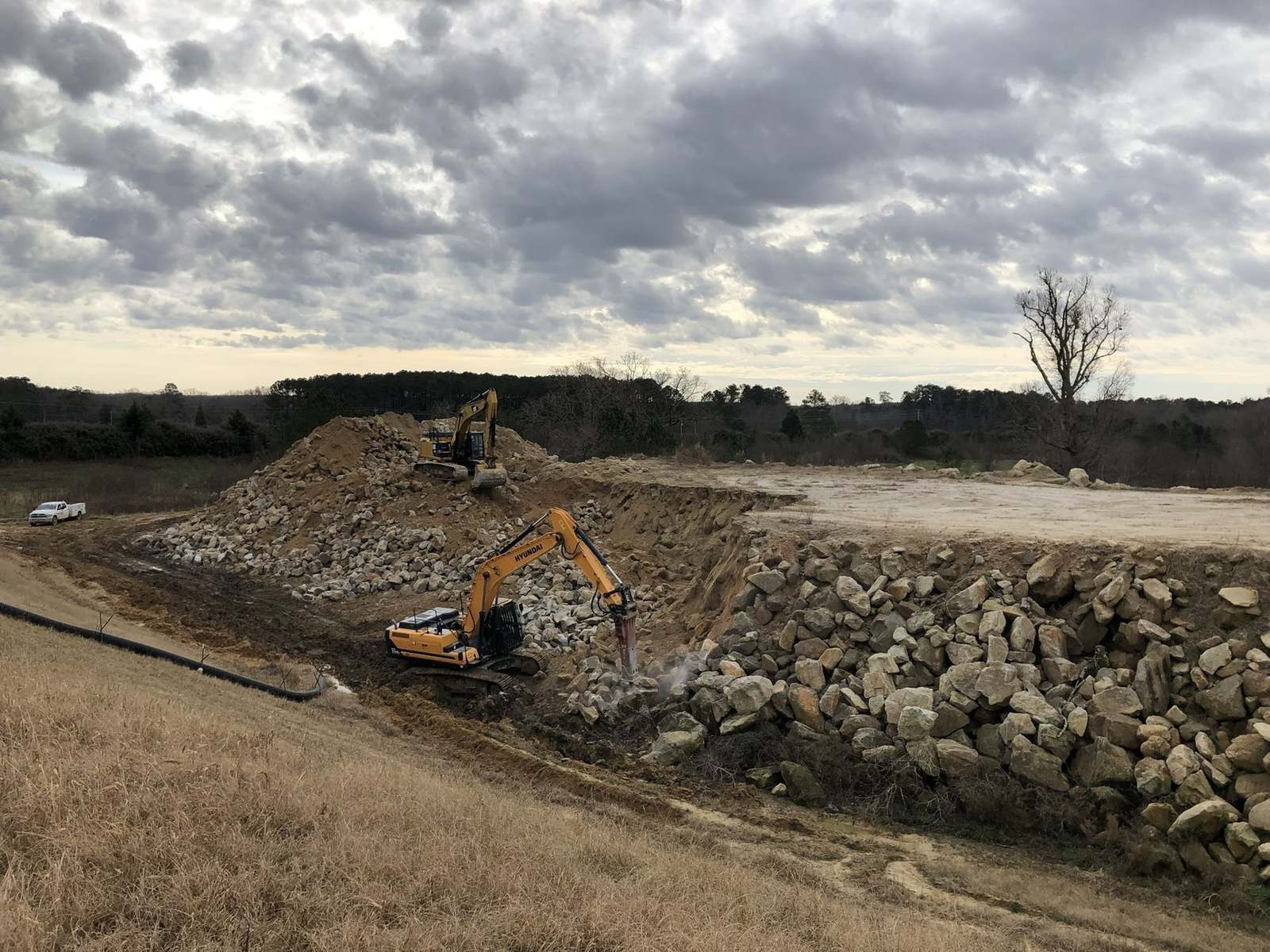 A-1 excavator with a hydraulic hammer breaking oversized rock at the Brownfield Road Landfill