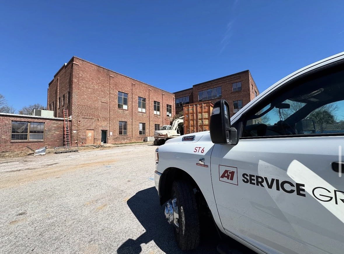 A-1 service truck in front of a brick mill building being demolished