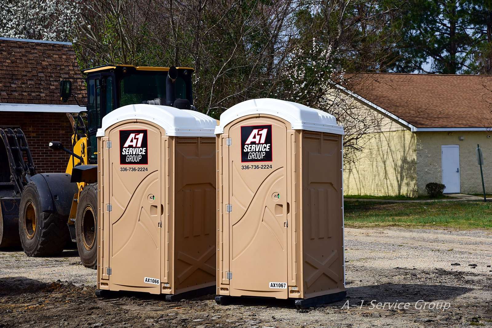 Two A-1 portable toilets on a job site next to a wheel loader