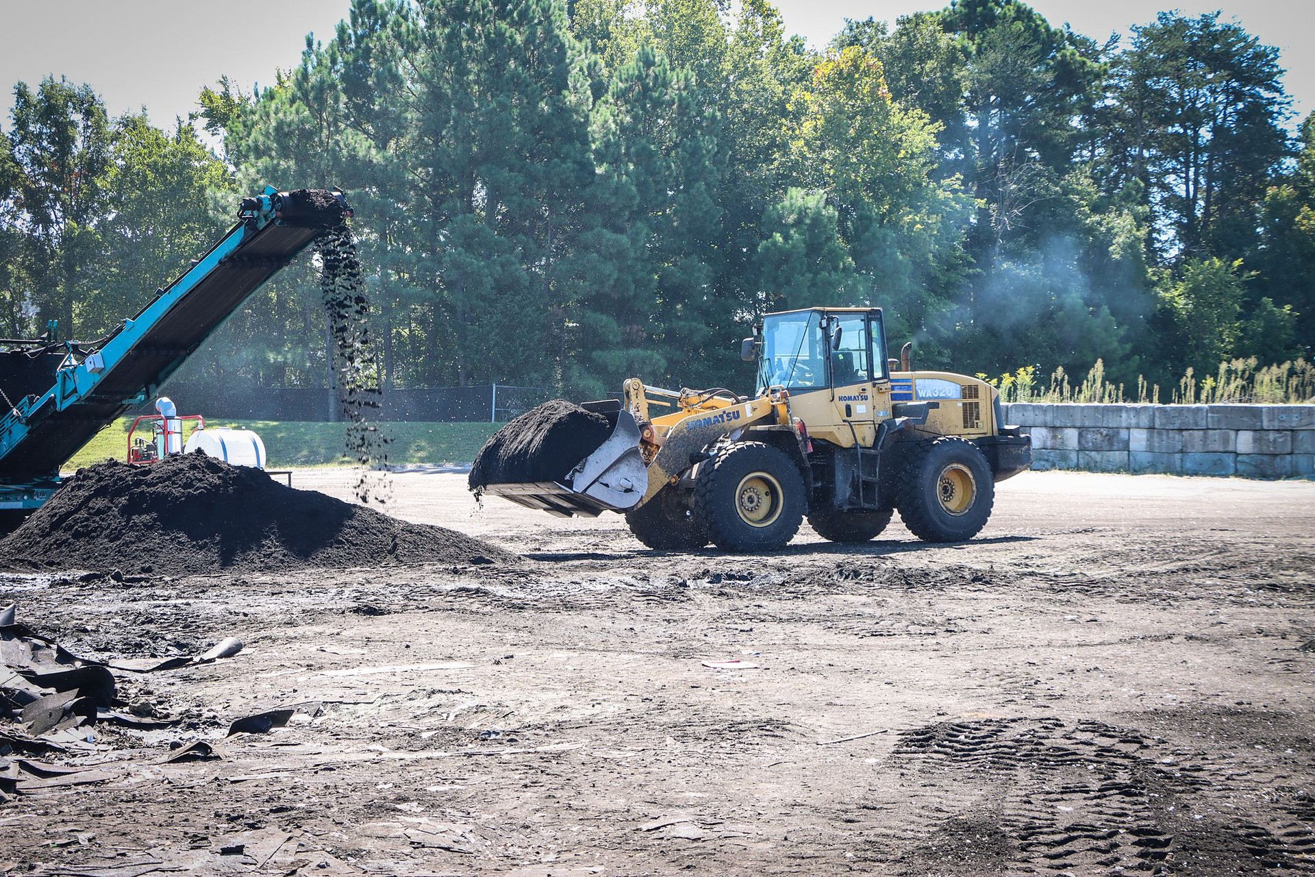 Loader stockpiling ground roofing shingles