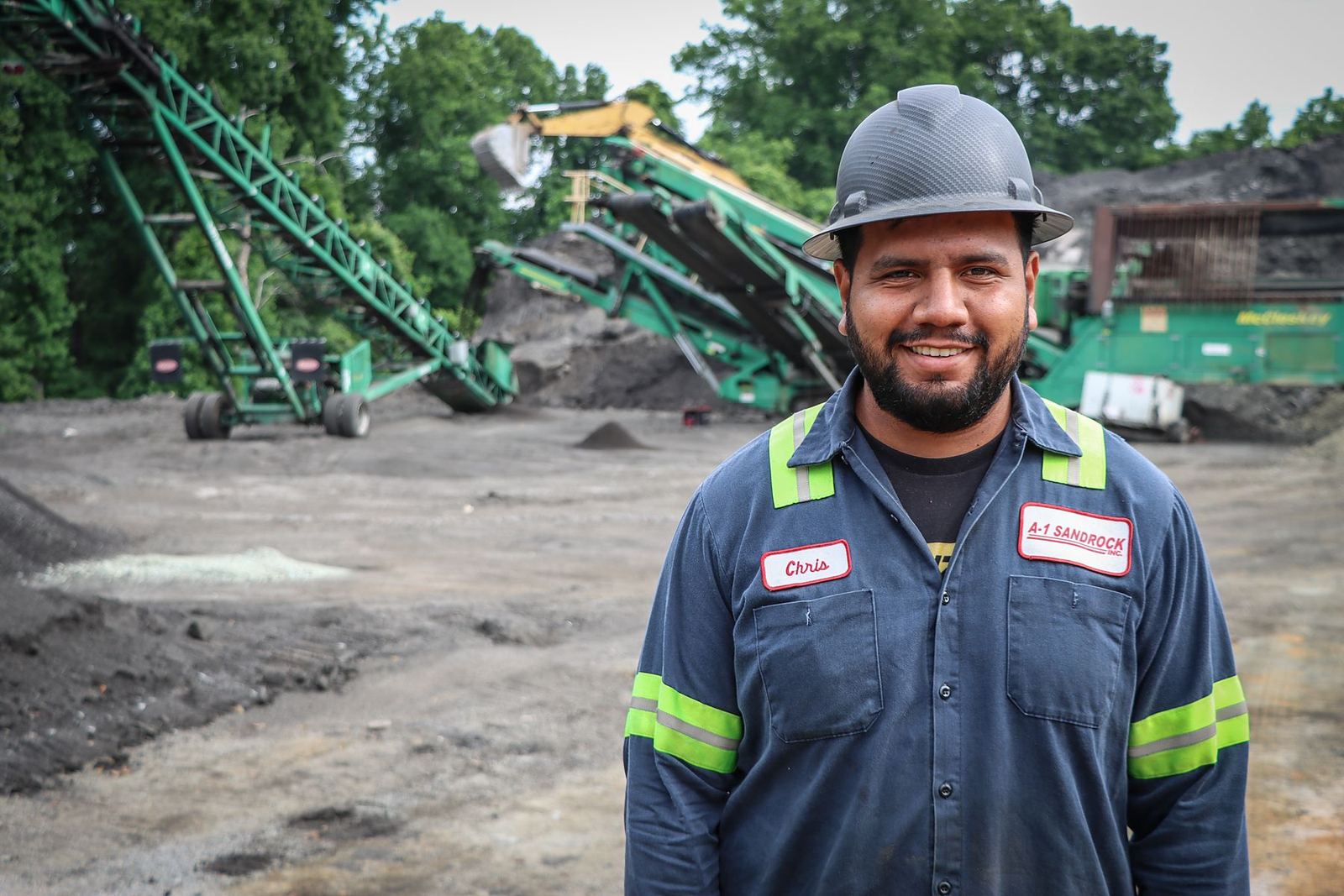 Chris, an A-1 team member since 2017, in a hard hat at an asphalt crushing site