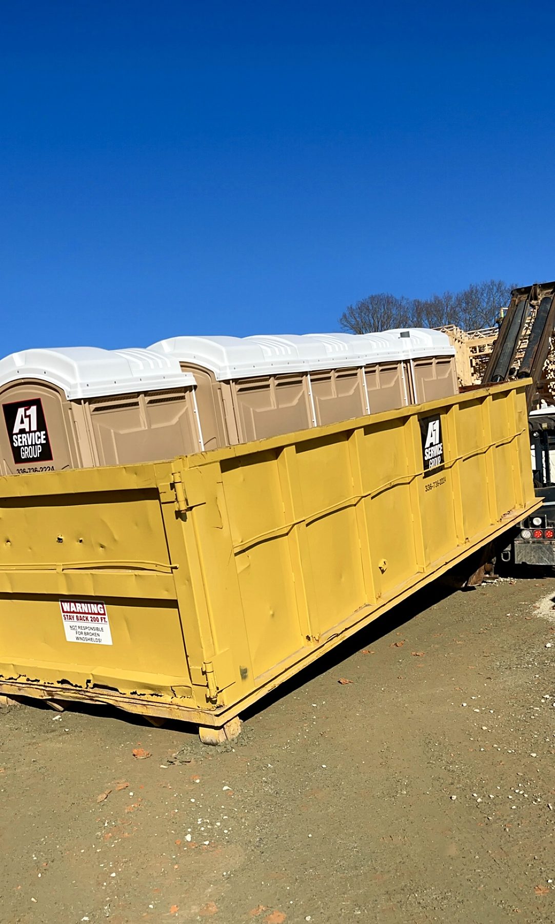 A-1 portable toilets riding to a job site inside a roll-off dumpster