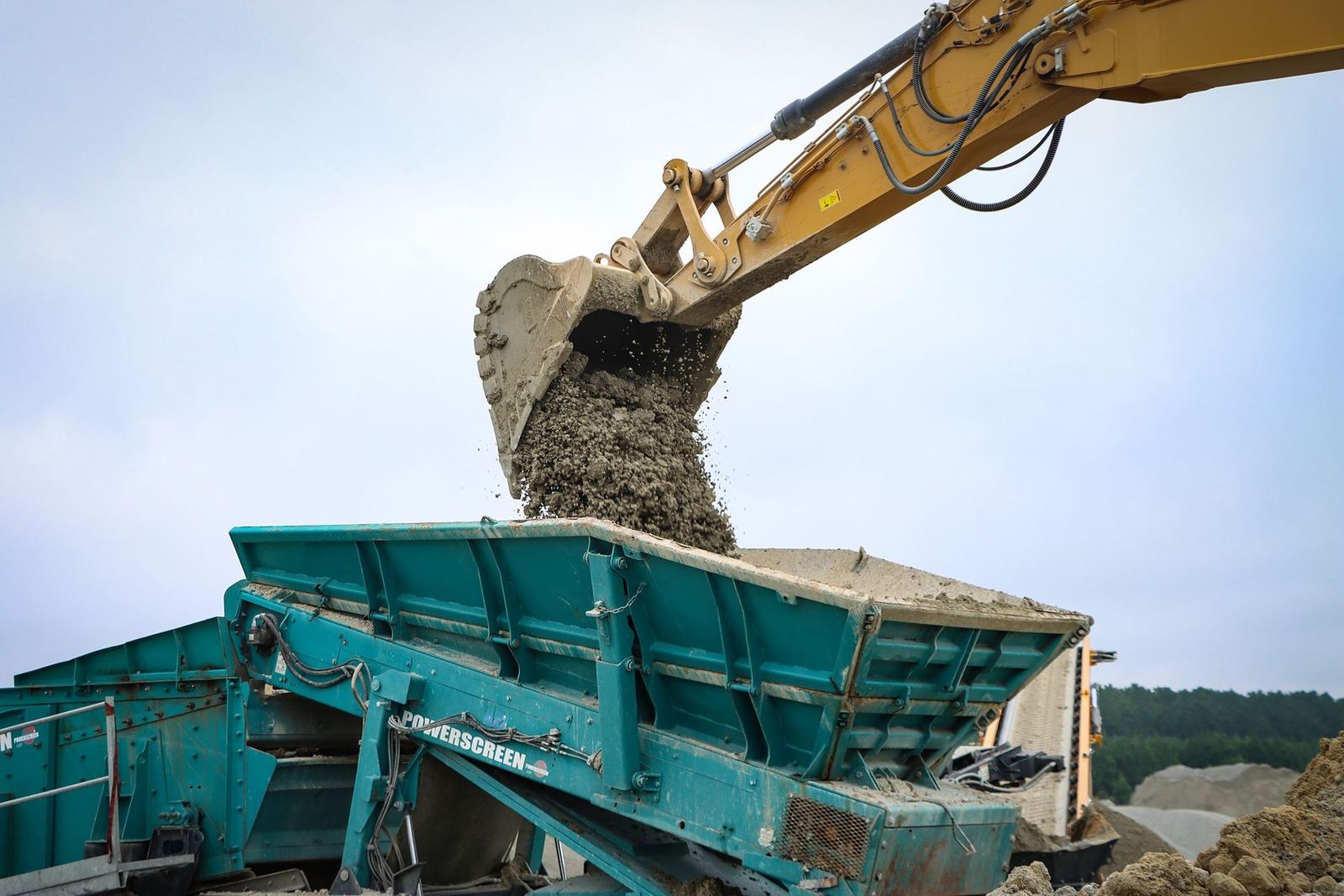 A-1 CAT excavator dropping a bucket of rock into a jaw crusher