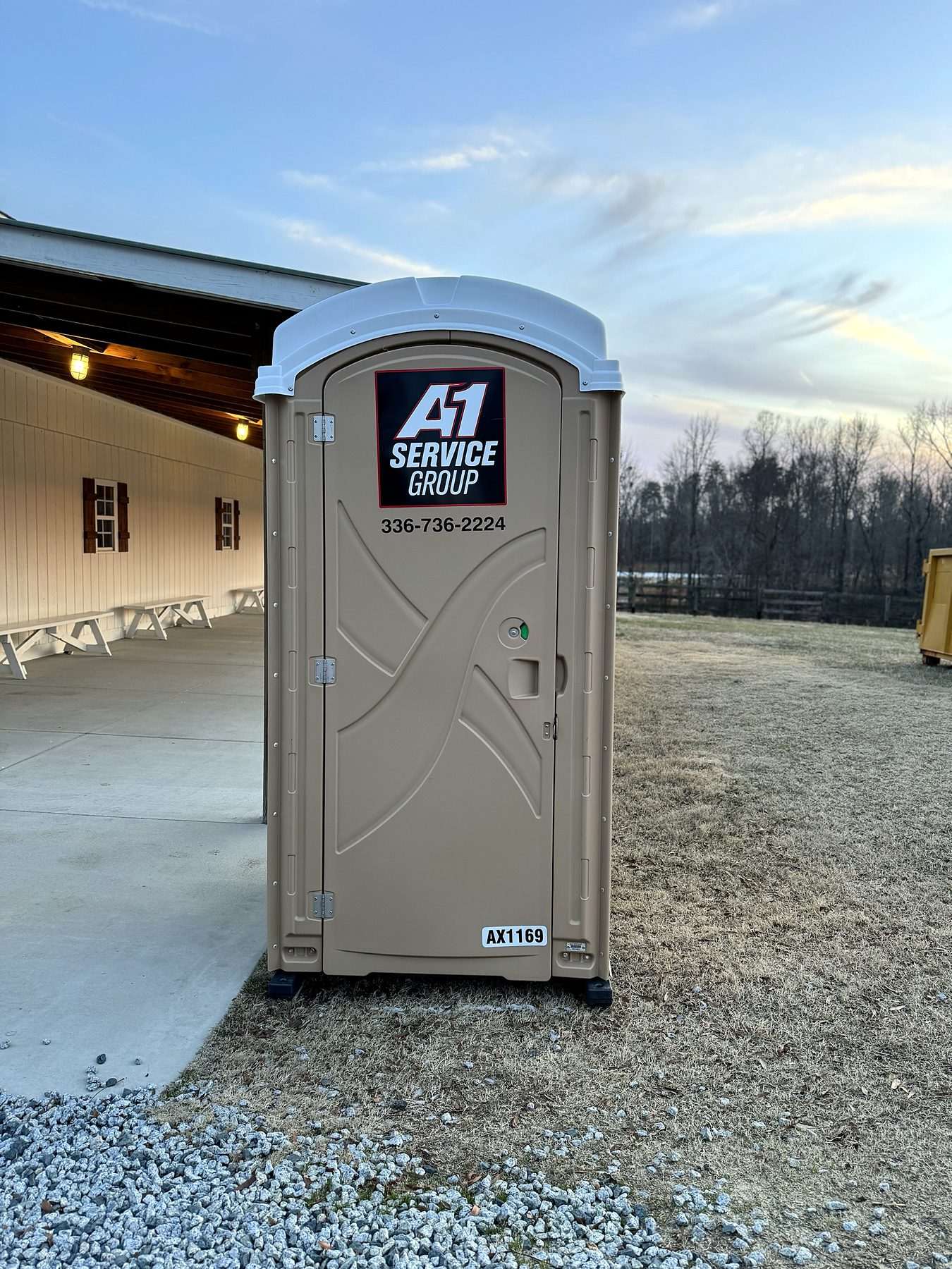 A-1 portable toilet beside a farm pavilion at dusk