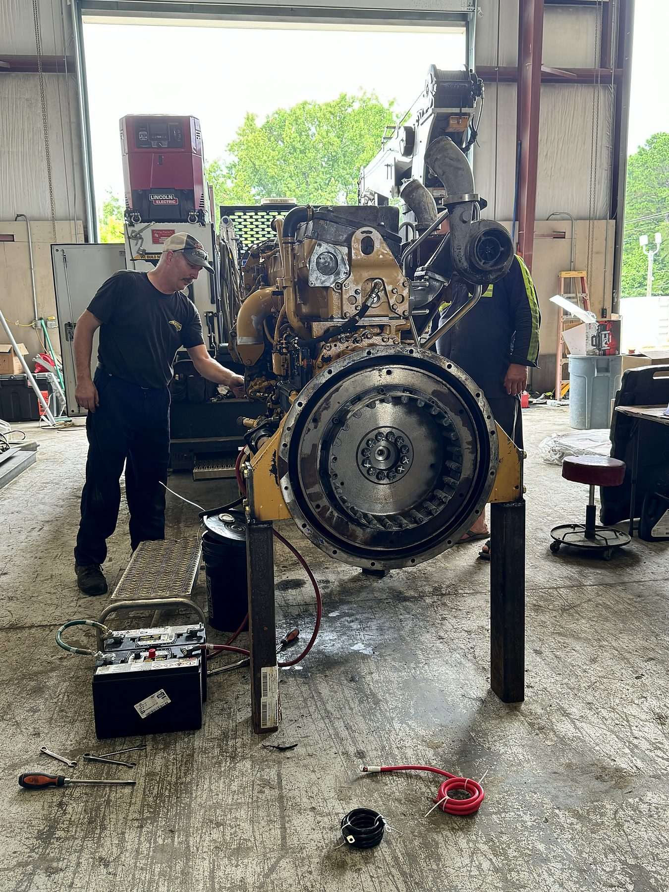 Mechanics working on a CAT engine on a stand in the A-1 shop