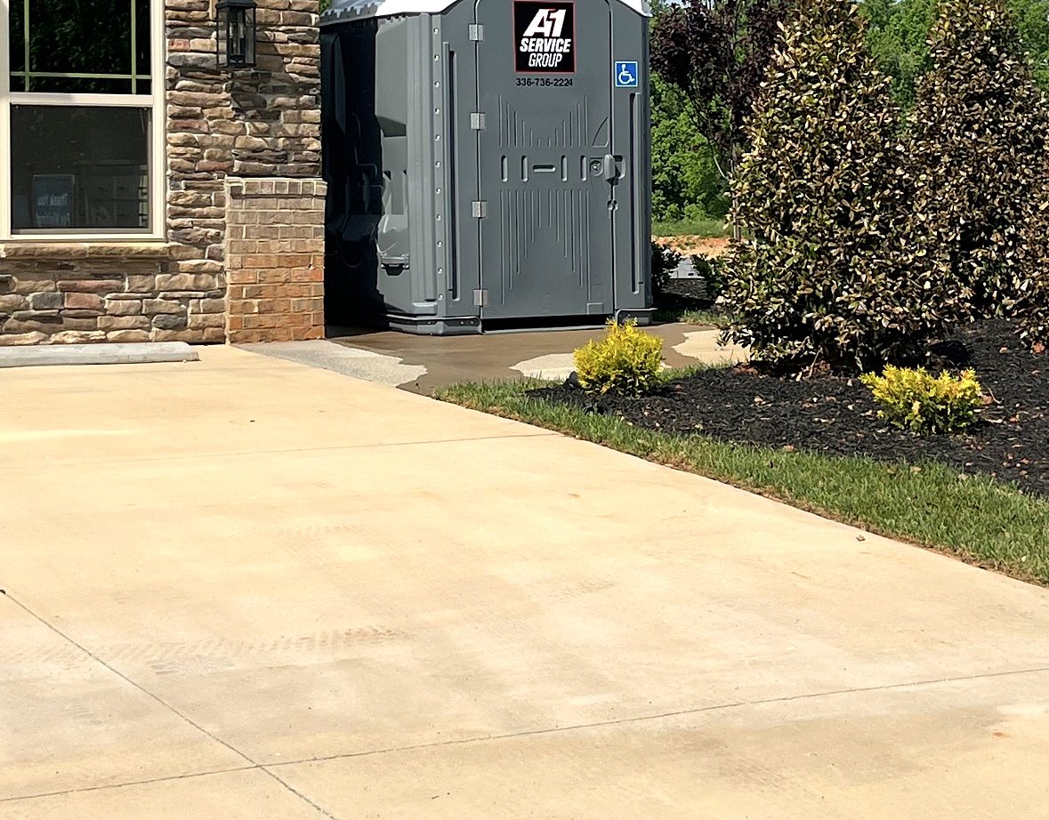 A-1 driver giving a thumbs up beside an ADA portable toilet on the service truck