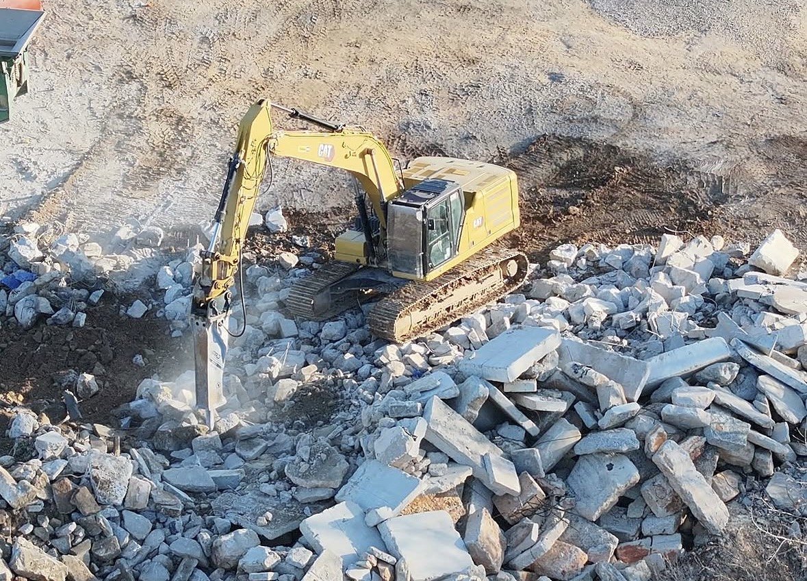 A-1 CAT excavator with a hydraulic hammer breaking concrete slabs