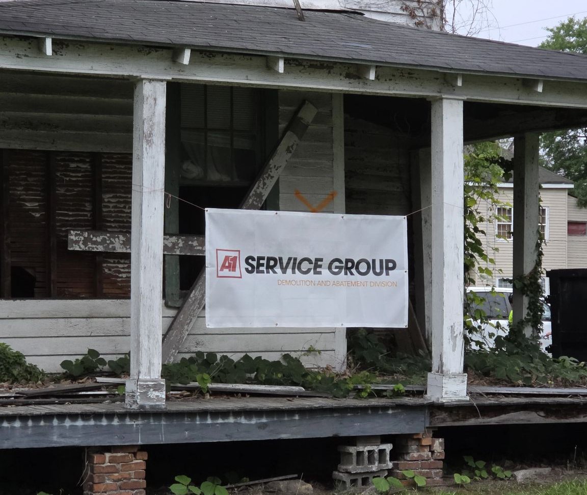 A-1 Service Group Demolition and Abatement Division banner on the porch of an old house before demolition