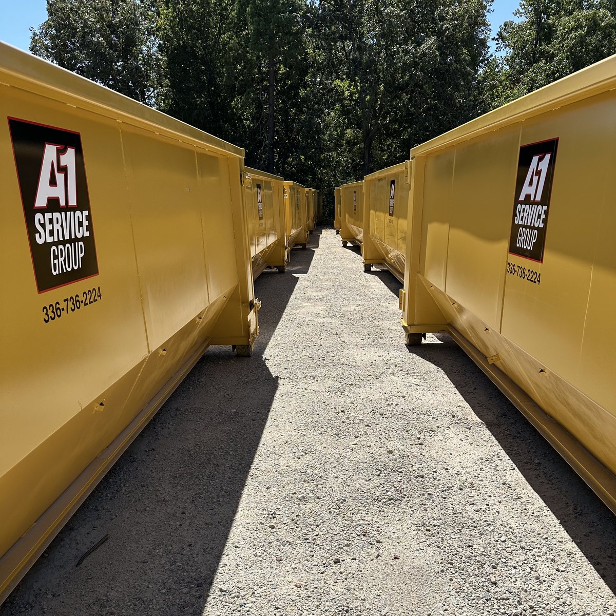 Rows of yellow A-1 Service Group roll-off dumpsters in the yard