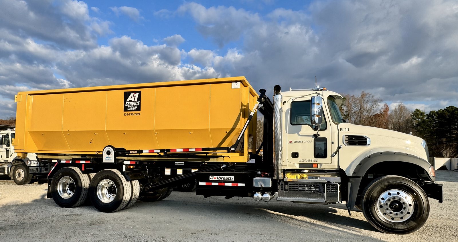 A-1 Service Group roll-off truck R-11 carrying a yellow dumpster
