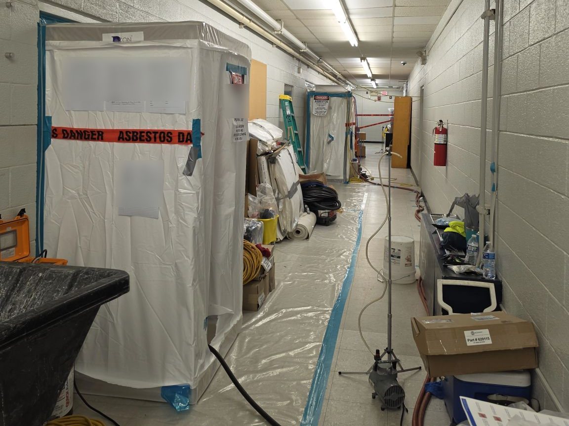 Decontamination unit and asbestos warning tape at the entrance to an abatement work area