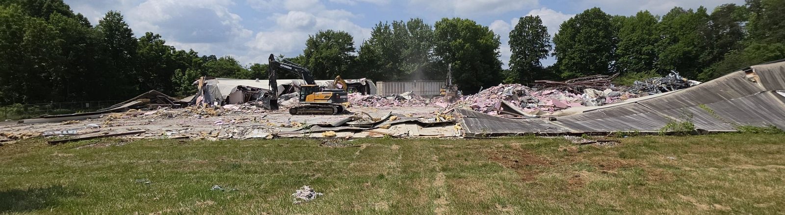 Excavators clearing a large commercial building demolition site down to the slab