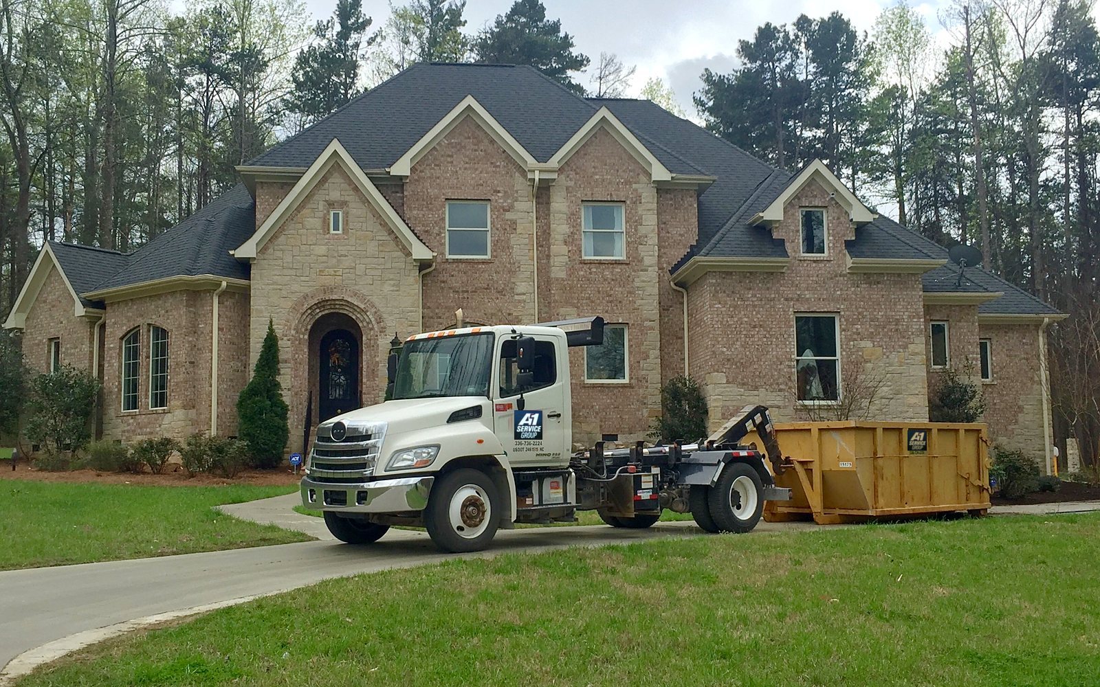 A roll-off truck delivering a dumpster to a home in the Triad