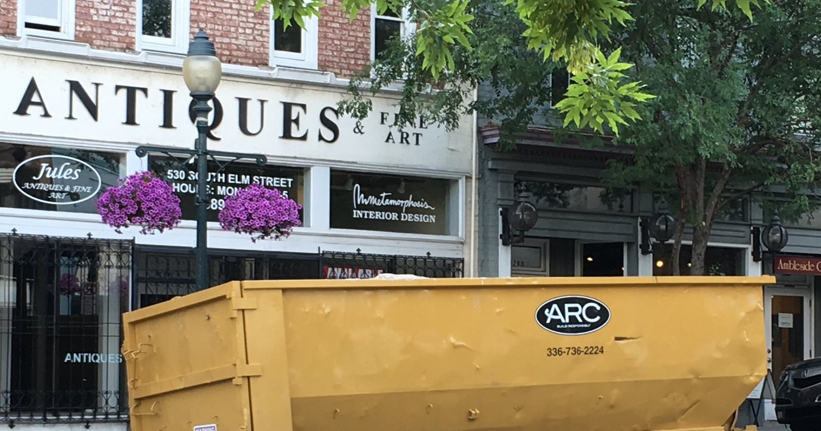 A yellow roll-off dumpster on South Elm Street in downtown Greensboro, NC